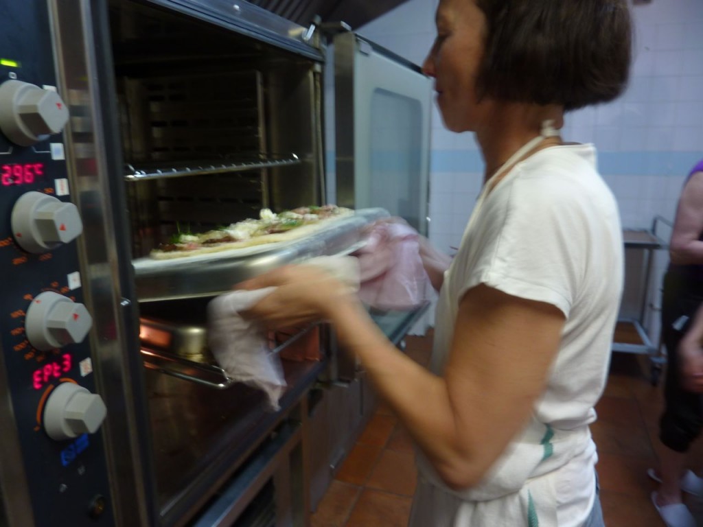Susan Regis putting pizza in oven - luxury bike tours italy